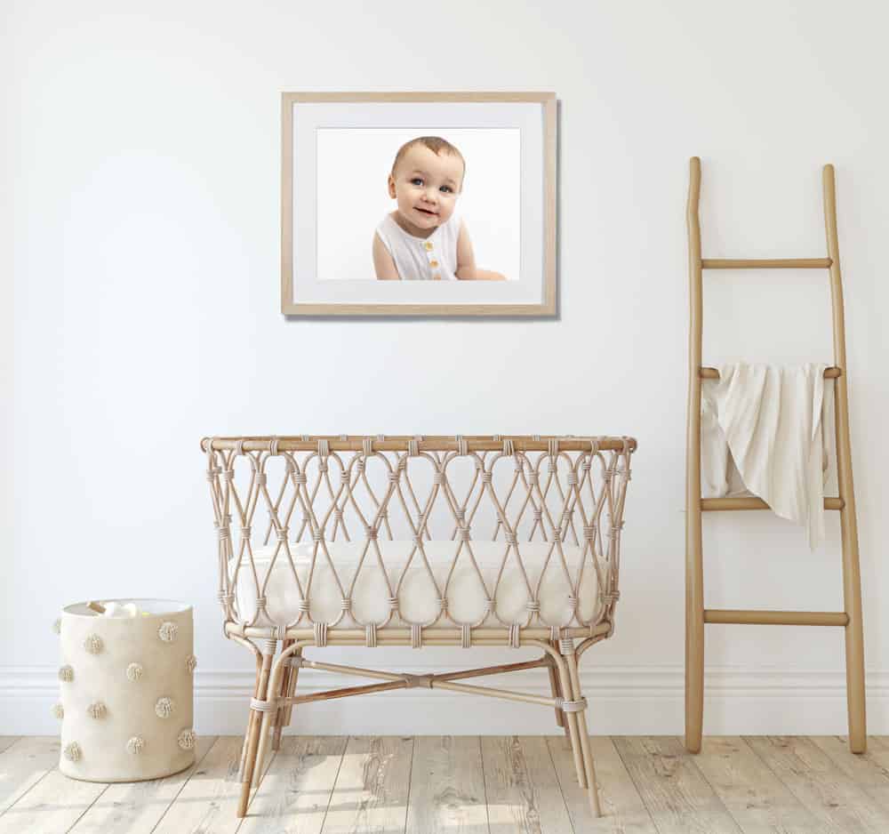 Framed print of baby hanging on wall of nursery
