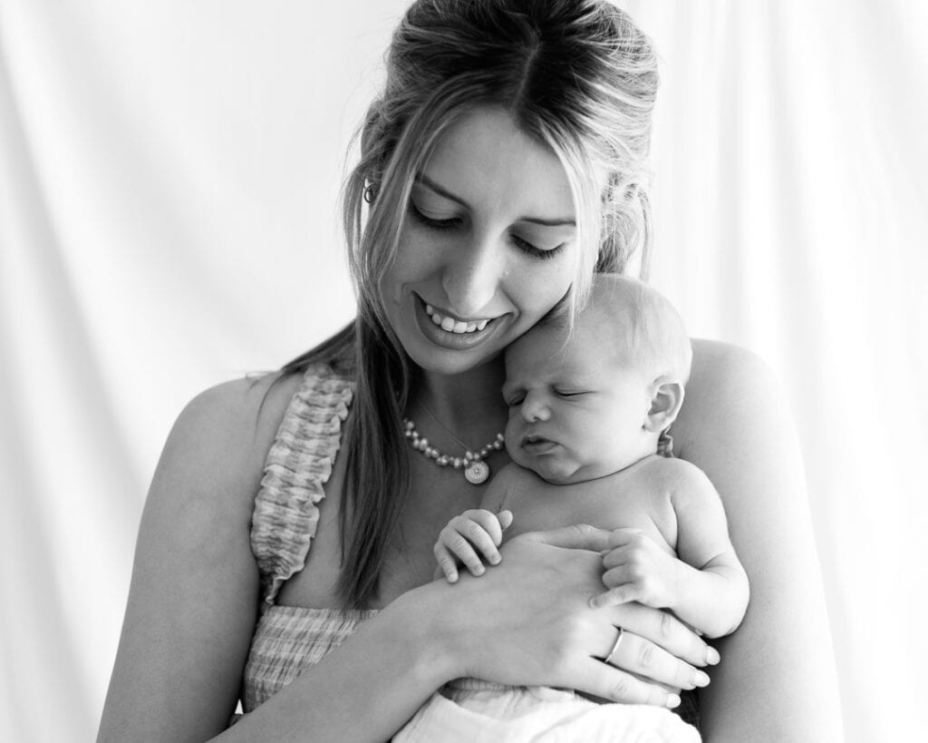 New mother cuddles baby boy during newborn photo shoot