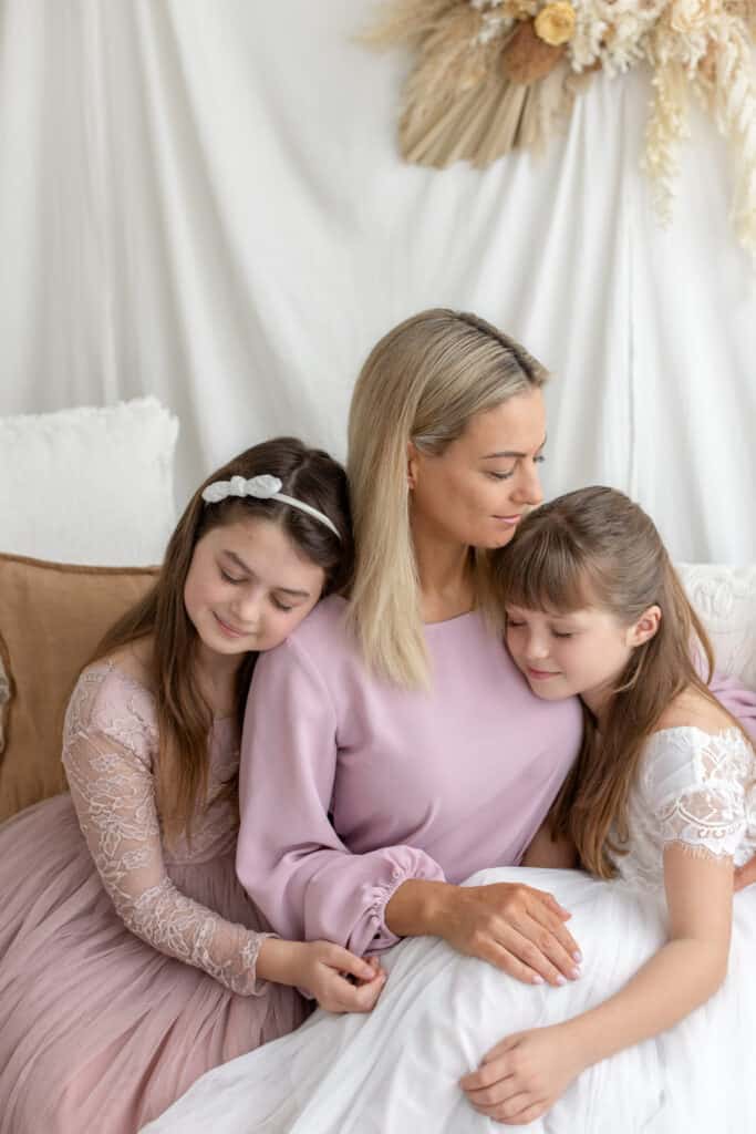 Mother and your daughters embracing during photography session in boho styled studio