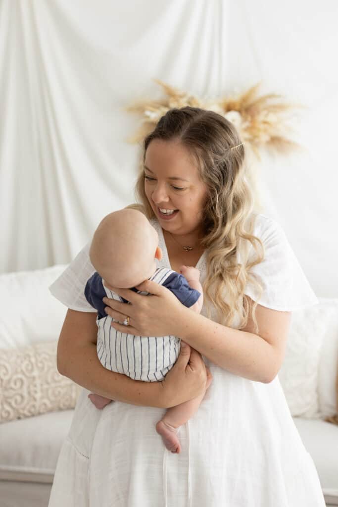 Mother in boho photography studio cuddles and smiles at her baby boy